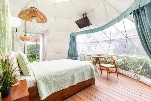 瓜纳卡斯特Ubuntu Glamping的一间卧室配有一张床、一张桌子和一个窗户。