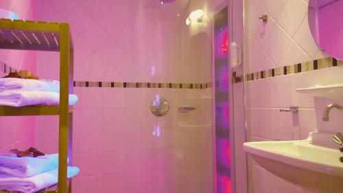 霍勒姆Hotel Dolores Ameland的粉红色的浴室设有淋浴和水槽