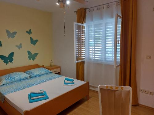 波斯蒂拉Apartments with a parking space Postira, Brac - 2911的一间卧室设有一张床,墙上设有一扇带蝴蝶的窗户。