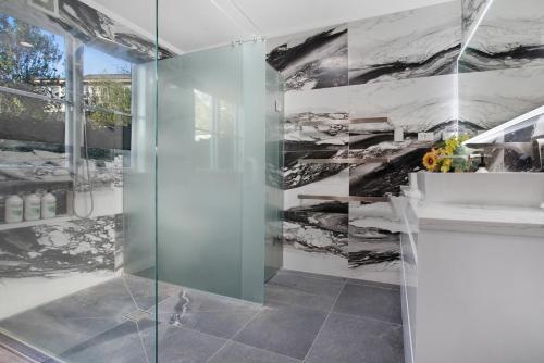 奥克兰Urban Oasis in Remuera, Auckland的浴室设有玻璃淋浴间和大理石墙