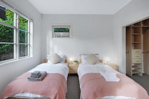 奥克兰Urban Oasis in Remuera, Auckland的配有2张床的白色墙壁和窗户客房