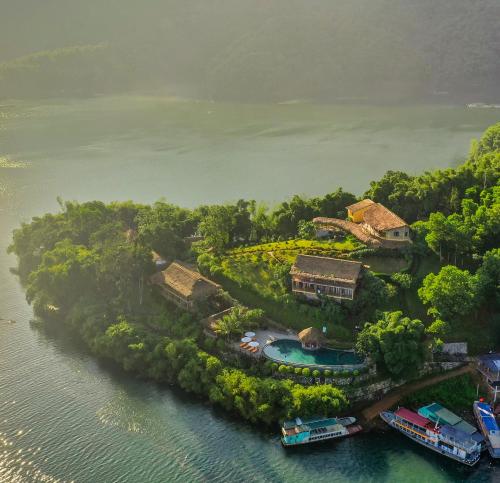 枚州县Mai Chau Hideaway Lake Resort的水中拥有房屋和船只的岛屿