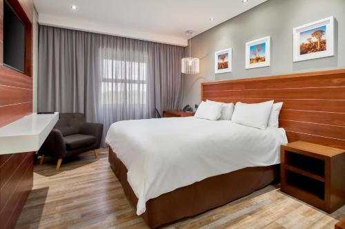 比勒陀利亚Protea Hotel by Marriott Pretoria Hatfield的酒店客房带一张大床和一把椅子