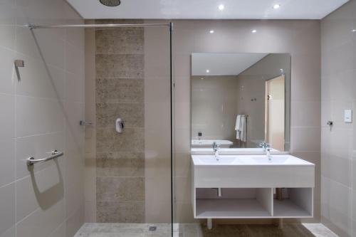 比勒陀利亚Protea Hotel by Marriott Pretoria Hatfield的一间带水槽和玻璃淋浴的浴室