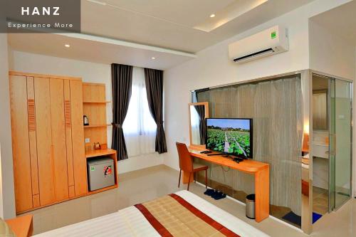 胡志明市HANZ Son Mi Hotel的一间卧室配有一张床和一张书桌及电视