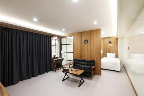 全州市Jeonju Urban Hotel的酒店客房配有床、沙发和桌子。