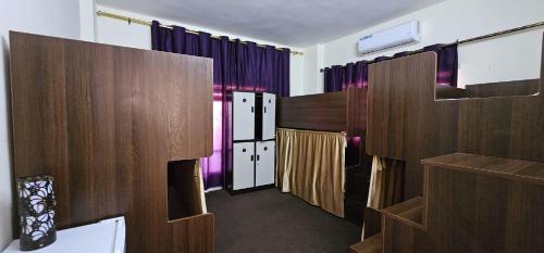 亚喀巴Pizza Street Hostel的一间设有紫色窗帘和木制隔板的客房