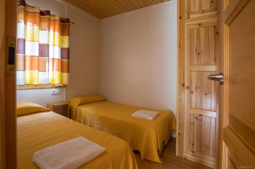 锡切斯锡切斯露营地的一间设有两张床、一个窗口和一扇门的房间