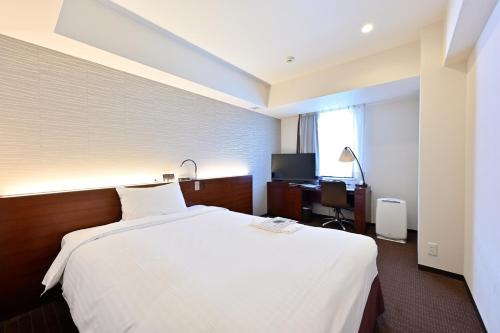 札幌札幌京阪酒店的一间酒店客房,配有一张白色的床和一张书桌