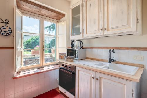 波卡里Villa Nobile Oasi的厨房配有白色橱柜、水槽和窗户。