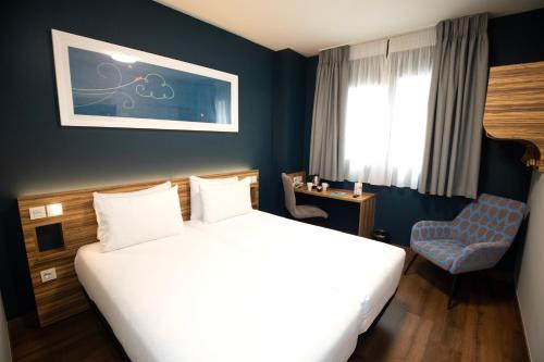 马德里Travelodge Madrid Metropolitano的配有一张床和一把椅子的酒店客房