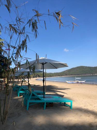 爱妮岛Zhaya's Beach & Cottages的海滩上的两张野餐桌和一把遮阳伞