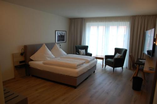 拜尔恩格里斯Altstadthotel Millipp的一间卧室配有一张床、两把椅子和电视