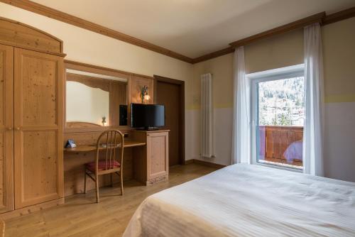 圣马蒂诺-迪卡斯特罗扎Hotel Colfosco的一间卧室配有一张床、一张书桌和一个窗户。
