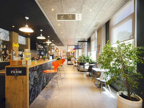 塞维利亚宜必思塞维利亚酒店的餐厅设有供应橙色凳子的酒吧