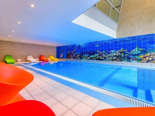 苏黎世诺富特苏黎世西城酒店的酒店的大型游泳池配有五颜六色的椅子