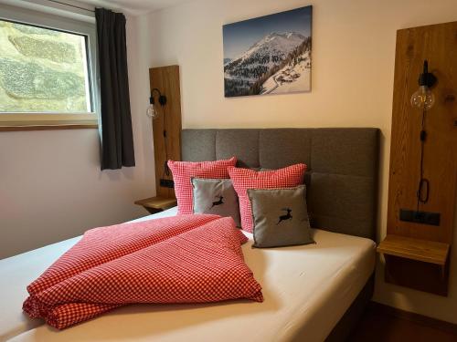 乌姆豪森Alp Apart Niederthai的一间卧室配有红色和白色枕头的床