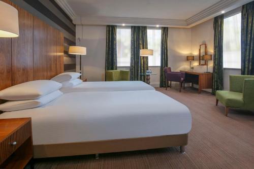 埃文河畔斯特拉特福英国埃文河畔斯特拉特福希尔顿逸林酒店的酒店客房设有一张大床和一张书桌。