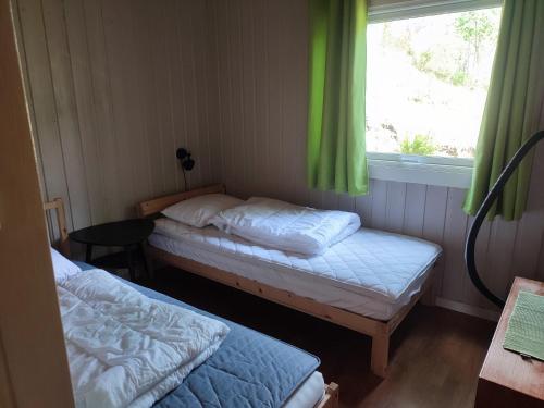 比尔克兰Strandheim Two-Bedroom Cottage的客房设有两张床和一个带绿色窗帘的窗户。
