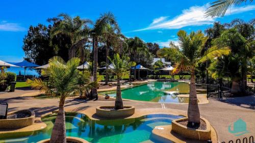 Cams WharfPlover Executive Deluxe Villa 25的度假村内棕榈树游泳池