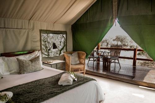 巴卢莱自然保护区腊肠树野生动物园露营地旅馆的一间卧室配有一张床,甲板配有桌子
