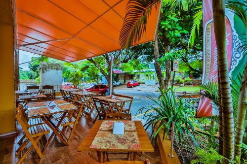伊瓜苏波萨达伊瓜苏套房旅馆的户外餐厅设有木桌和椅子,种有树木