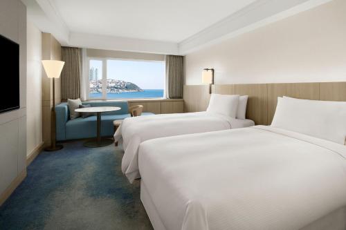 釜山The Westin Josun Busan的酒店客房设有两张床和窗户。