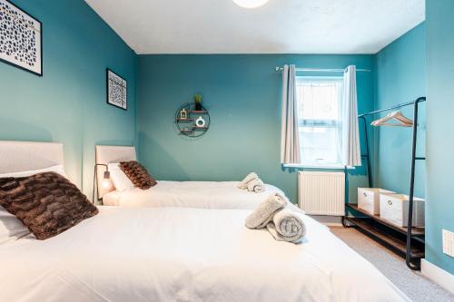 伊普斯威奇Shamrock House- 2 BR House, Free Parking & WIFI的蓝色墙壁客房的两张床