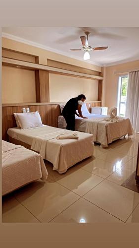 波苏斯-迪卡尔达斯Hotel Lux的在酒店房间做两张床的人