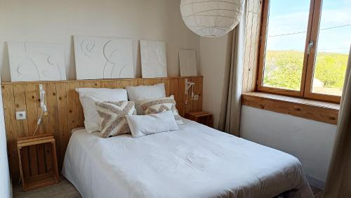 La Chapelle-EnchérieMaison ecologique en paille的卧室配有带枕头的白色床和窗户。