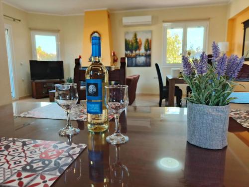 GalangádhosPazinos/Neveli Cottage的一张桌子上摆放着一瓶葡萄酒和两杯酒杯