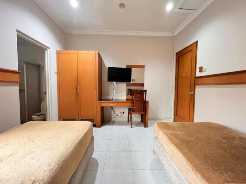 雅加达大篷车酒店的一间卧室配有两张床和一张书桌及电视