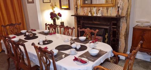 米德尔顿因蒂斯代尔Belvedere House的餐桌、白色的桌布、椅子和壁炉