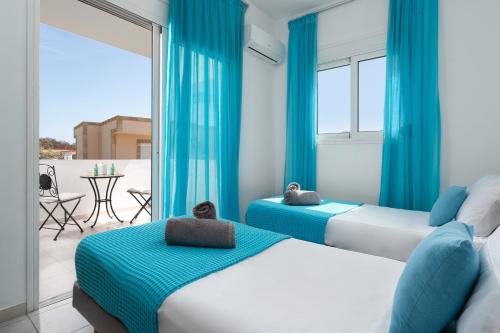 拉多斯Villa Bella with Private Pool and Hot Tub的配有两张床铺的蓝色窗帘和阳台