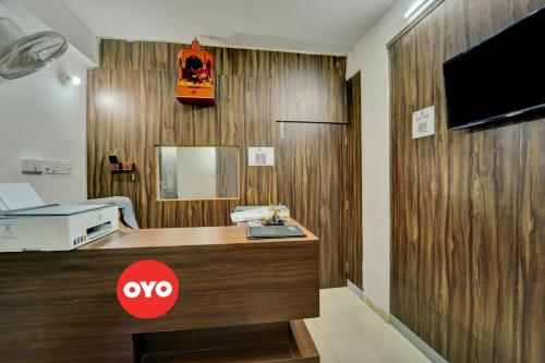 巴特那OYO Flagship Hotel Celebrate Inn的客房设有一张书桌,木墙上配有电视。