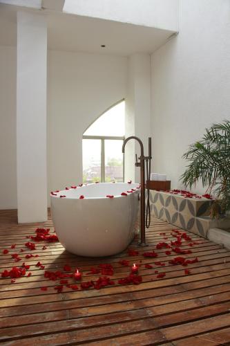 巴兰基亚Country International Hotel的浴室位于地板上,配有带红色玫瑰花瓣的浴缸。