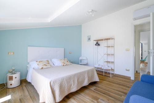 马尔塔Esmeralda - Mansarda con vista mozzafiato的卧室配有白色的床和蓝色椅子
