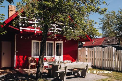 德布吉Słoneczne domki的一间红色的房子,前面设有一张野餐桌