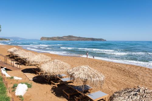 斯塔罗斯The Mini Beach Hotel的海滩上设有椅子和草伞,还有大海