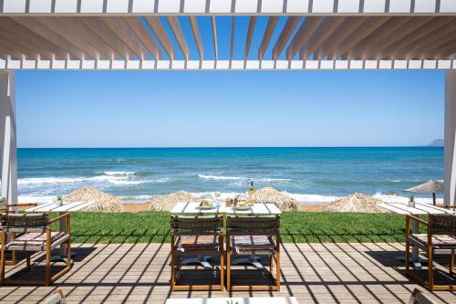 斯塔罗斯The Mini Beach Hotel的一个带桌椅的庭院和海滩