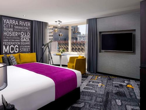 墨尔本Pullman Melbourne City Centre的一间酒店客房,配有一张床和一台电视