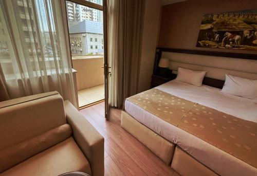 巴库Smith Hotel Baku的一间卧室配有一张床、一张沙发和一个窗口