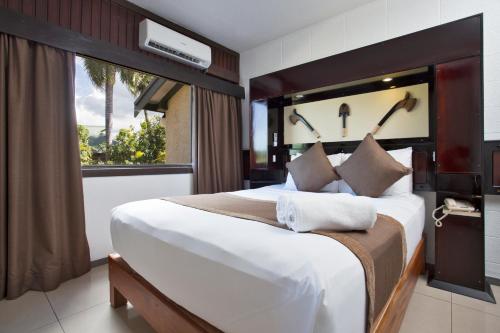 南迪斐济盖特威酒店的一间卧室设有一张大床和大窗户