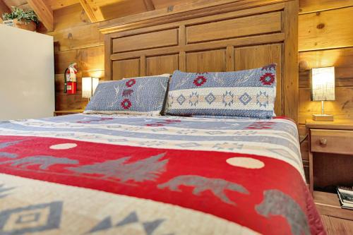 加特林堡Cozy Cabin! Hot Tub, King Bed, Fireplace, & Pool的一张带红色和蓝色被子和枕头的床