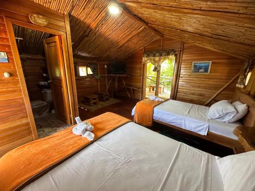 Puerto Velasco IbarraEl Pajas的小木屋内一间卧室,配有两张床