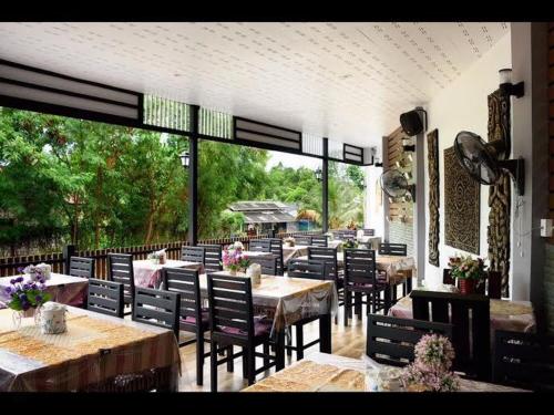 柴老海滩普莱艾塔里度假村的餐厅设有桌椅和大窗户。