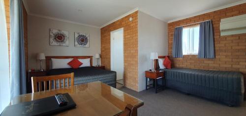 德尼利昆Centrepoint Motel Deniliquin的酒店客房设有两张床、一张桌子和一张书桌。