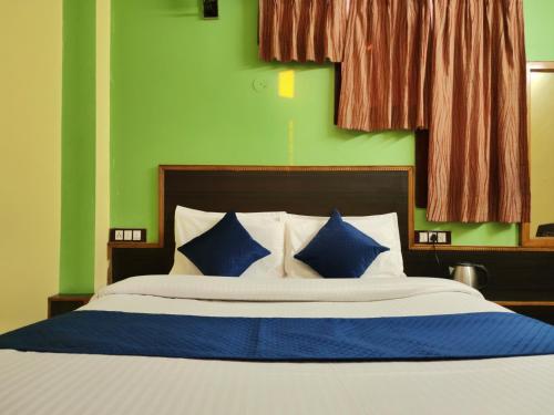 西姆拉Hotel Tirupati Regency Near Mall Road的一张带蓝色和白色枕头的床和绿色的墙壁