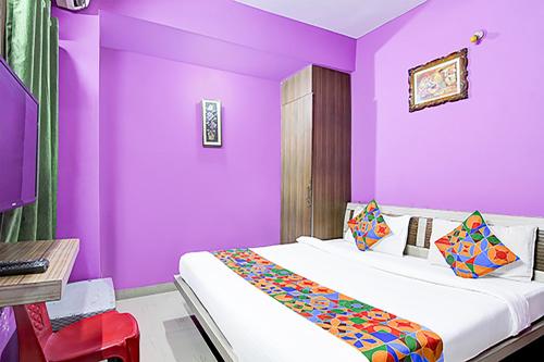 兰奇FabHotel Star Lotus的一间卧室设有紫色的墙壁和一张带桌子的床