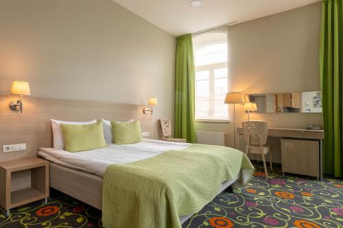 维尔纽斯兰宁凯城市酒店的酒店客房带一张大床,带绿色窗帘